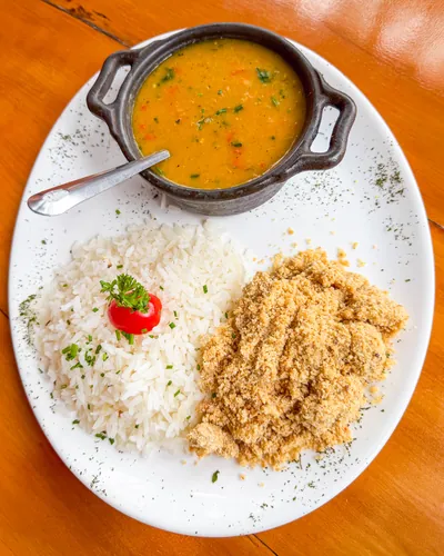 Bobó de camarão servido em panela de barro, com arroz branco e farofa de banana