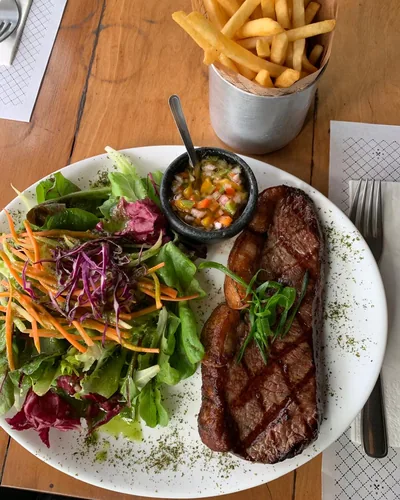 Steak de picanha grelhado com marcas de grelha, salada verde, vinagrete e batata palito