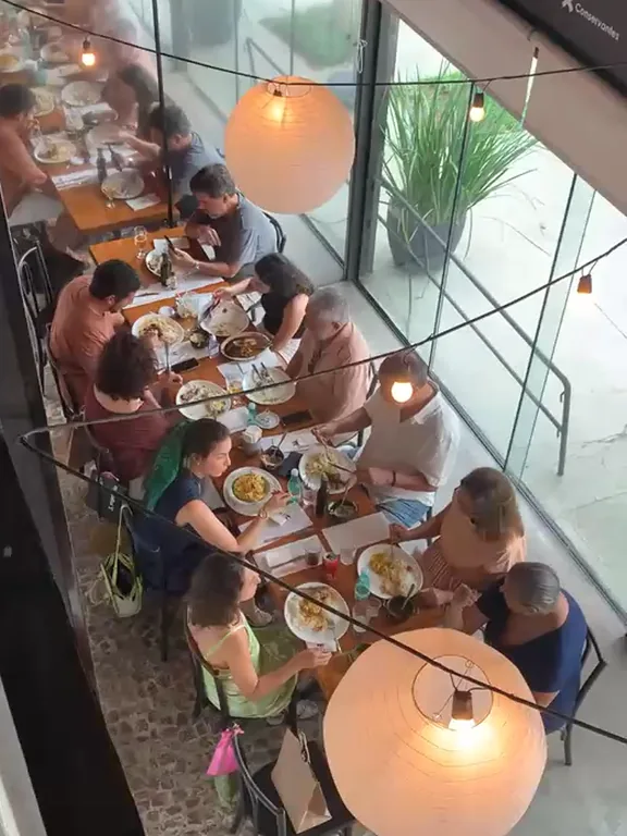 Mesa comprida ocupada de ponta a ponta no horário do almoço
