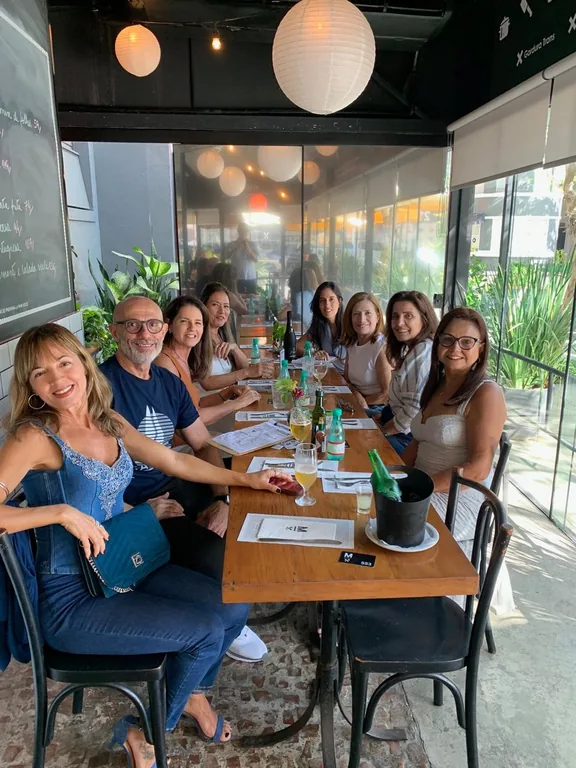 Grupo reunido em volta da mesa grande do Mironga, com vinho na mesa