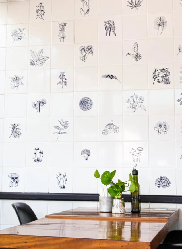 Mesa do Mironga junto à parede de azulejos com ilustrações botânicas