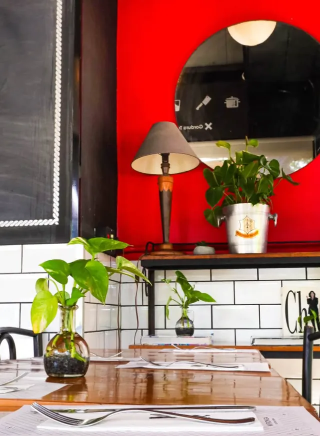 Salão interno do Mironga, com mesa posta e parede vermelha